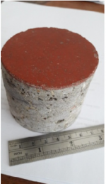 A core sample from the court floor beside a ruler, with its red surface on top