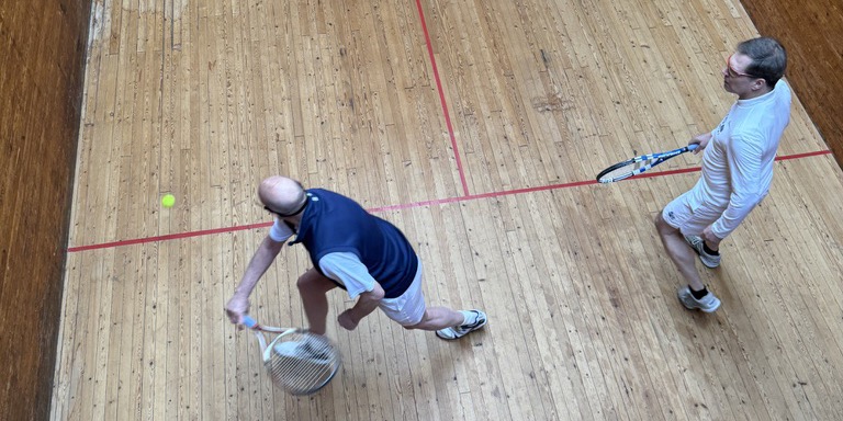 Two players in the Moreton Morrell squash tennis court, seen from the gallery